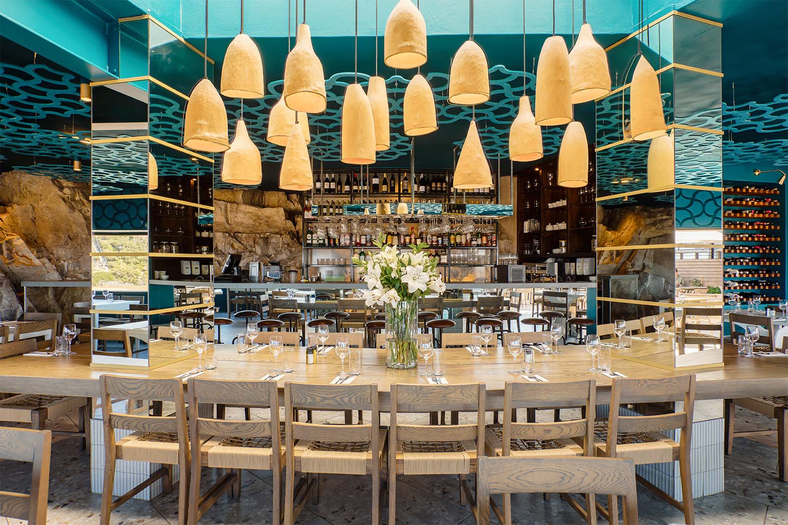 The Fat Fish dining room with sculptural pendant lights above a long communal table